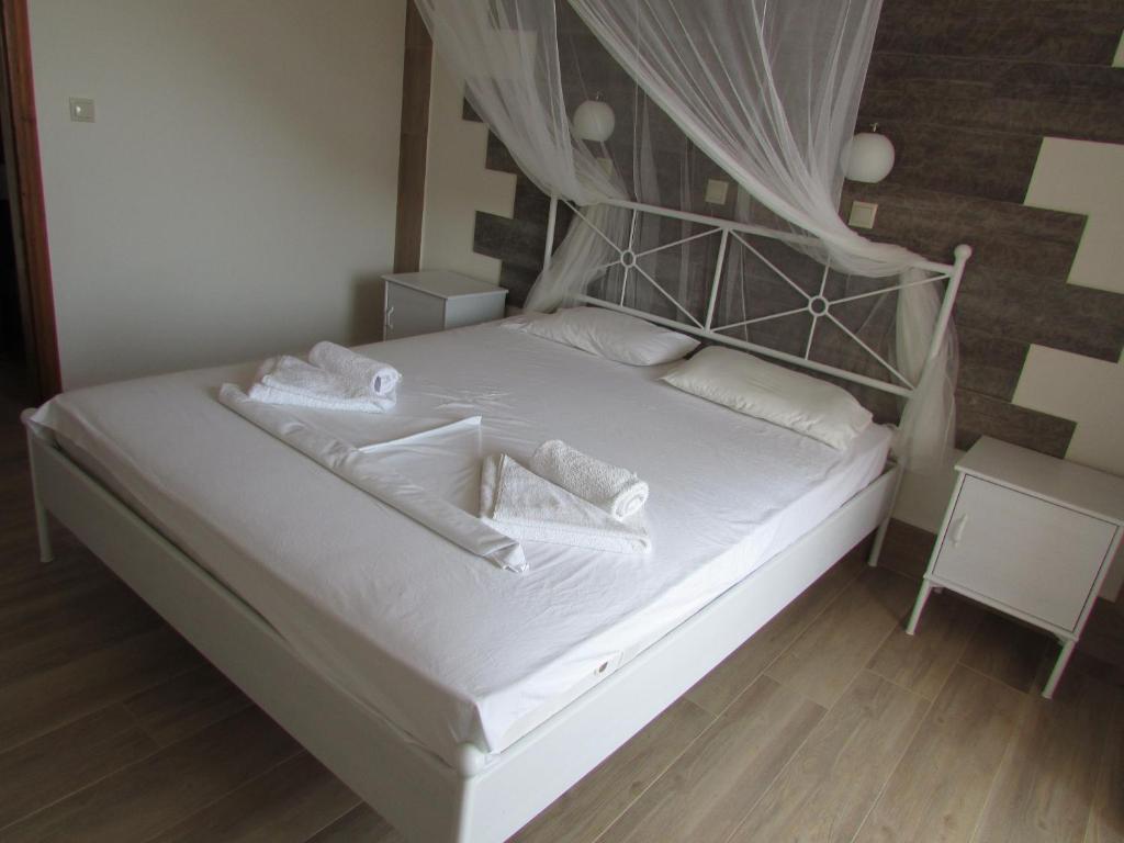 sypialnia z łóżkiem z białymi prześcieradłami i poduszkami w obiekcie Sevi Apartments w mieście Kefalos