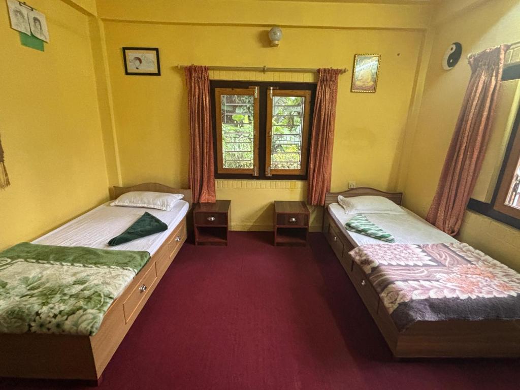 2 letti in una camera con pareti gialle e finestra di Baloo's Family homestay a Pokhara