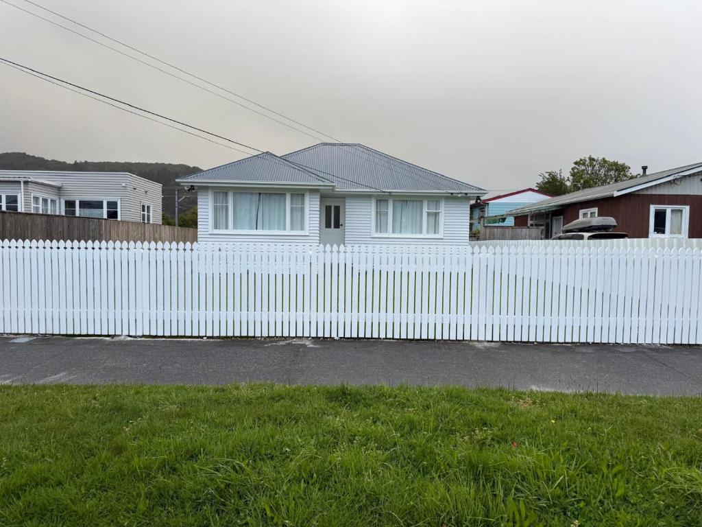 a white fence in front of a white house at Gee's House in Upper Hutt