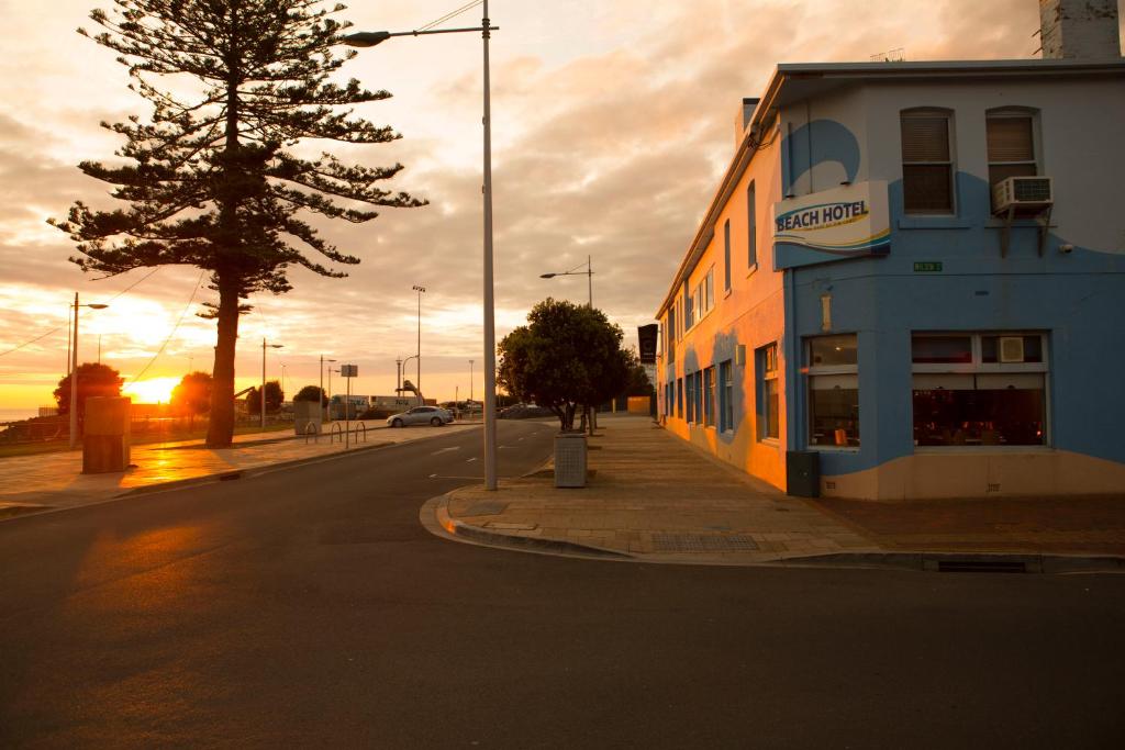 a building on the side of a street with a tree at Beach Hotel in Burnie