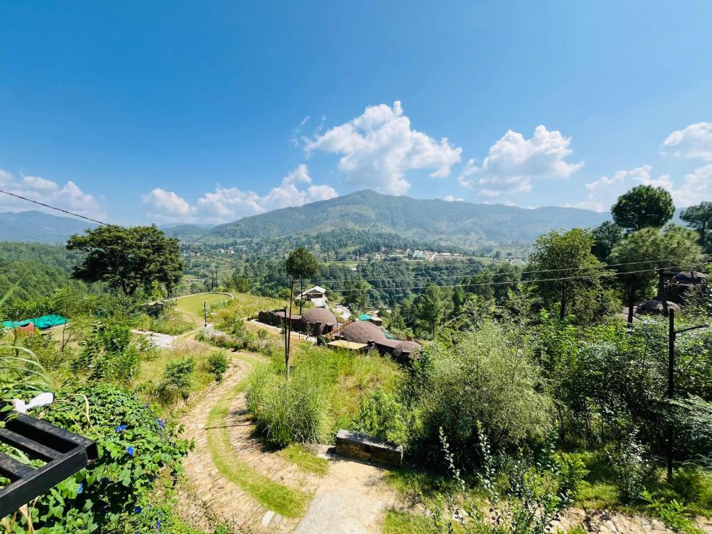 een onverharde weg die leidt naar een dorp met bergen op de achtergrond bij Villa Himalayan Trove in Jāmb