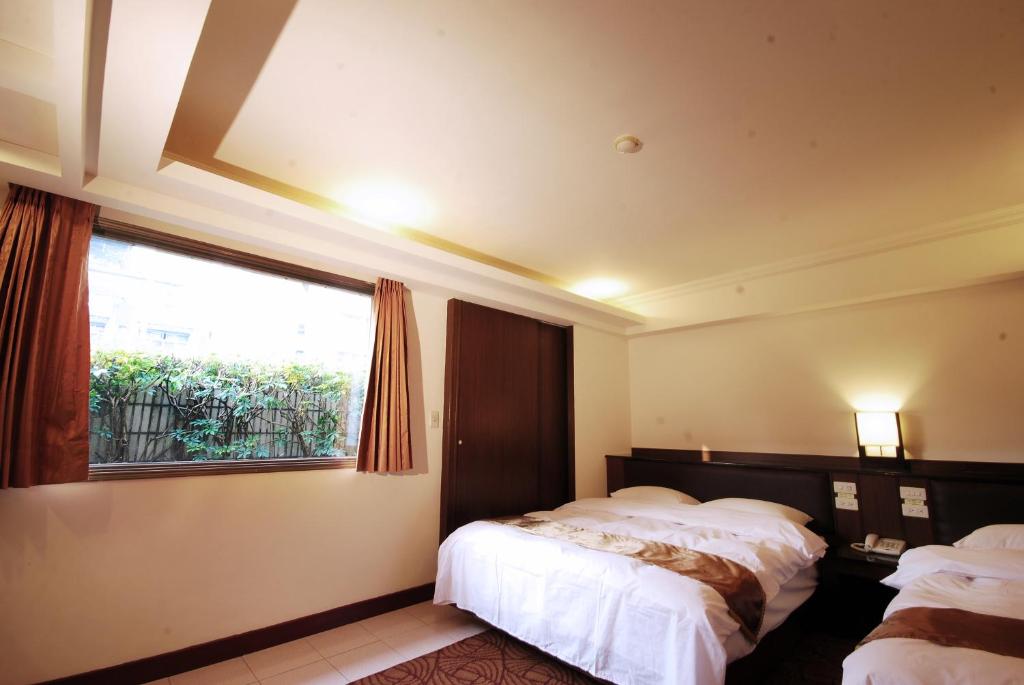 a bedroom with two beds and a window at The Enterpriser Hotel in Taichung
