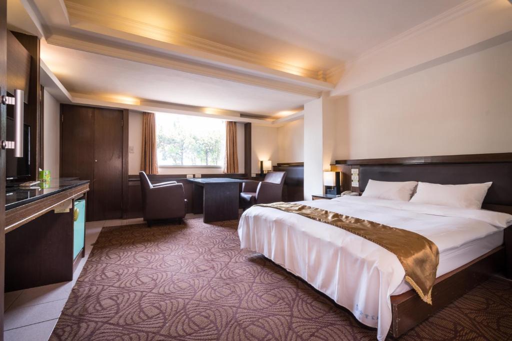 a hotel room with a large bed and a desk at The Enterpriser Hotel in Taichung
