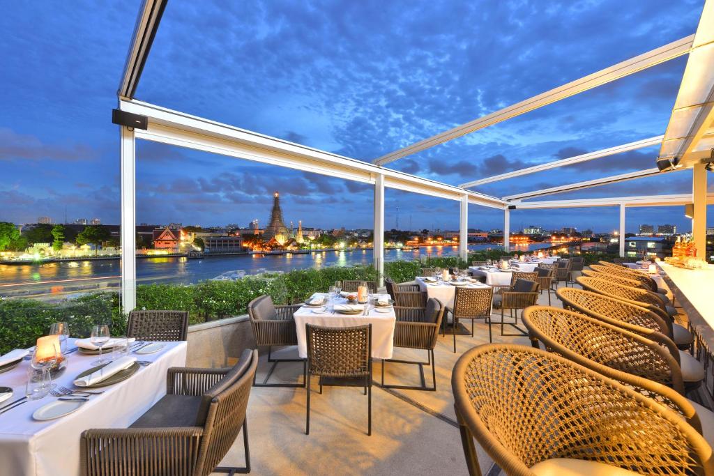فندق ريفا آرون بانكوك - SHA Extra Plus في بانكوك: مطعم به طاولات وكراسي ومطل على النهر