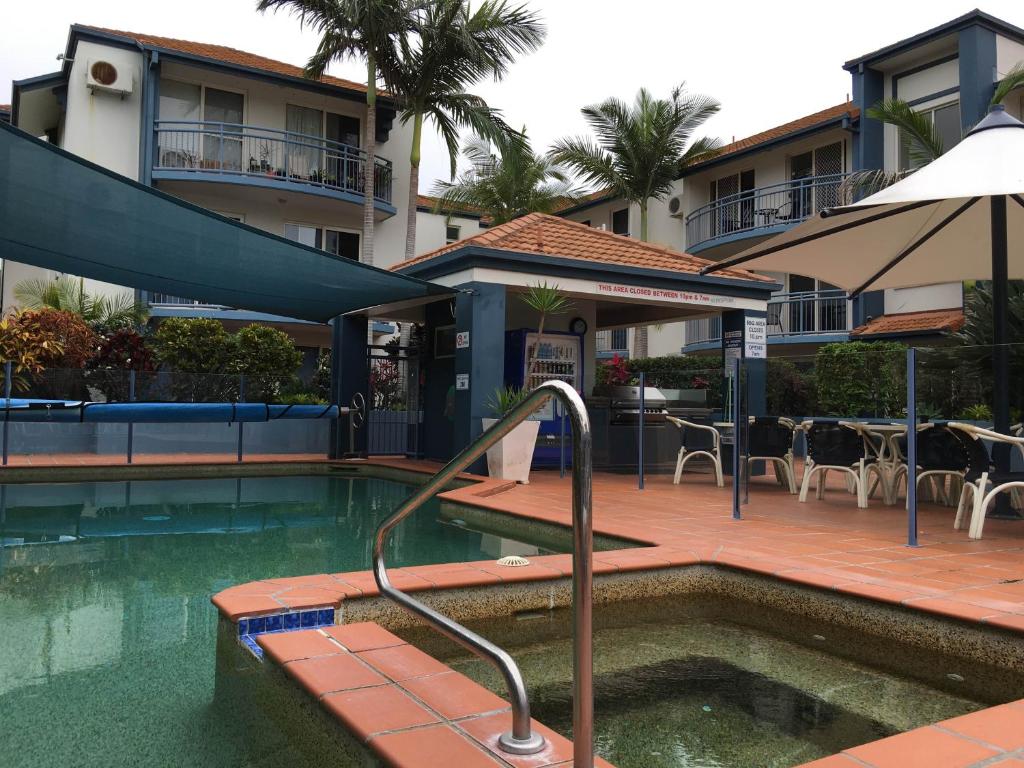 una piscina con sombrilla junto a un edificio en Santana Resort Surfers Paradise, en Gold Coast