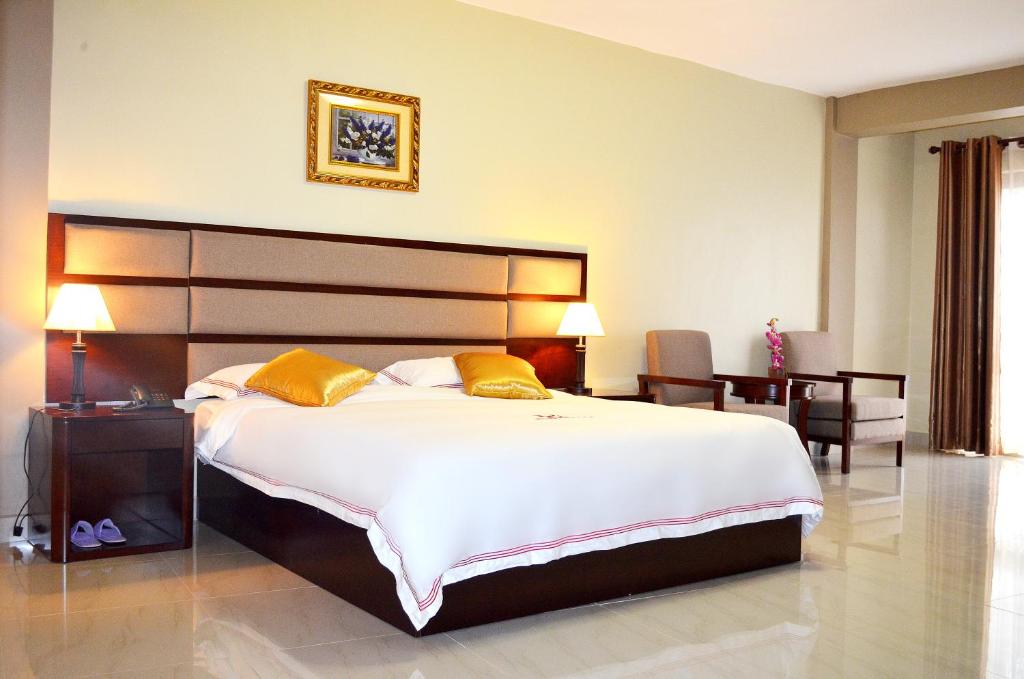 a hotel room with a large bed and a desk at Hillside Plaza Hotel in Kampala