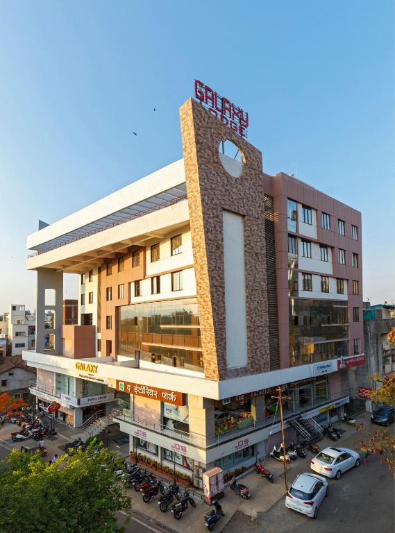 a building with cars parked in a parking lot at Hotel Galaxy Inn Kolhapur in Kolhapur