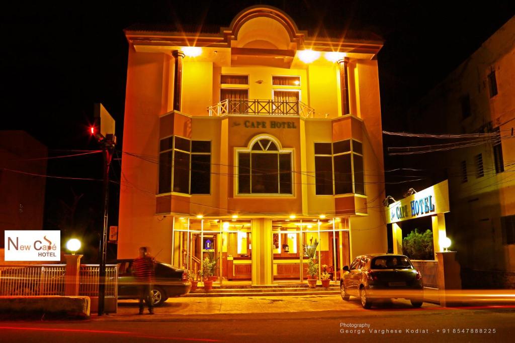 a building with a car parked in front of it at night at New Cape Hotel in Kanyakumari