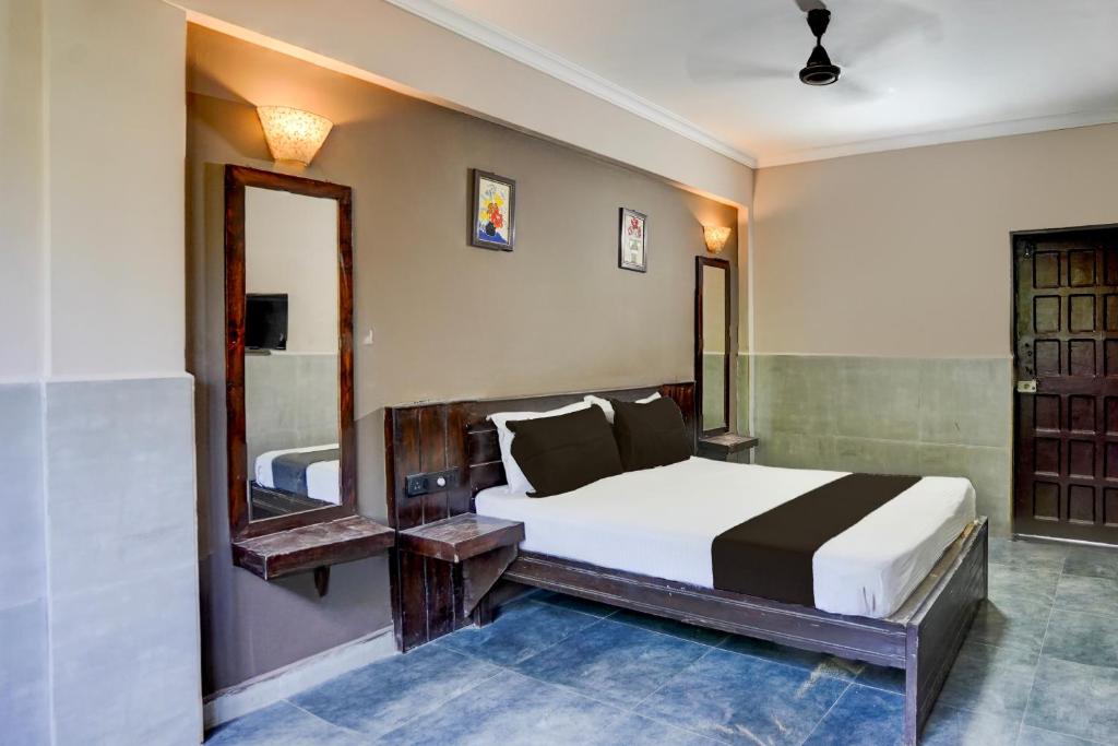 een slaapkamer met een groot bed en een spiegel bij Hotel O Calangute-Baga Crossway Formerly Rustic Village in Calangute