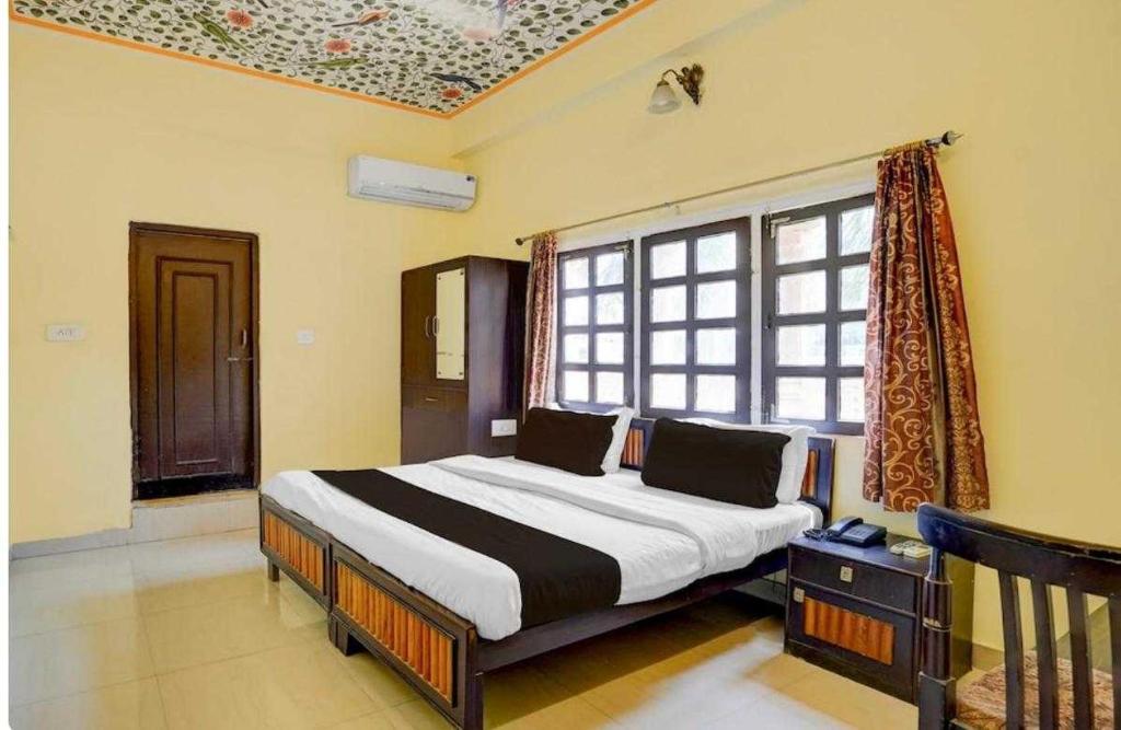 ジャイプールにあるHotel O Jagatpura Central Railway Station Jaipurのベッドと大きな窓のある寝室