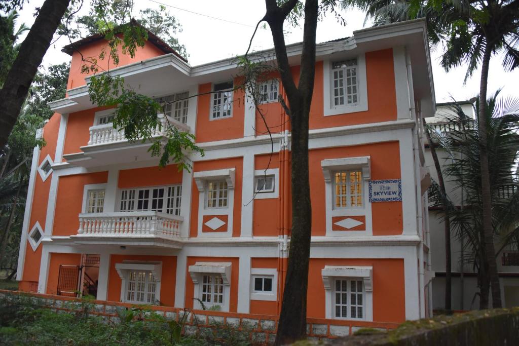 an orange and white building with trees in front of it at SkyView Villa in Candolim