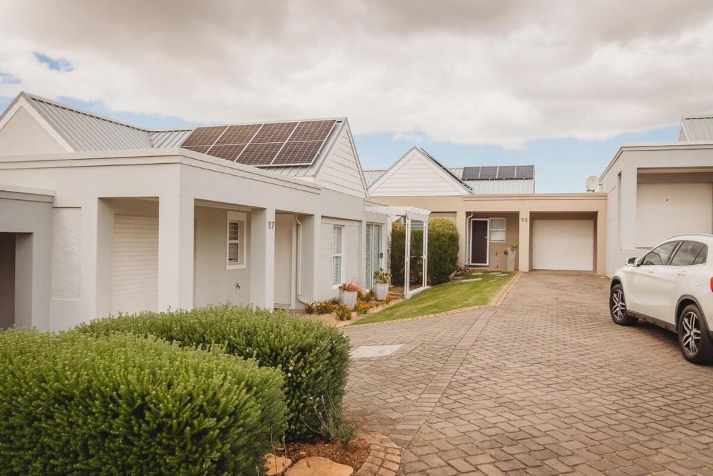 a white car parked in front of a house with a solar roof at Palms Manor on Kingswood Golf Estate in George