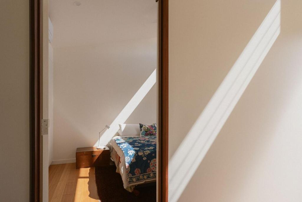 a mirror in a room with a bed and a staircase at Bird & Beach - 2 minutes walk to the beach in Suffolk Park