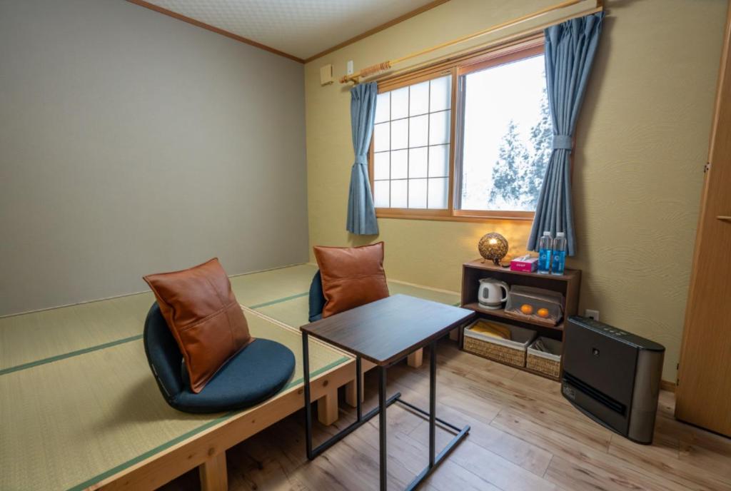 a room with two chairs and a table and a window at urara house guesthouse in Wada