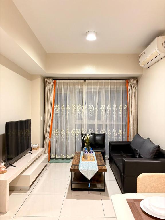 a living room with a black couch and a tv at 2BR Sunset View Deluxe Suite in Manila