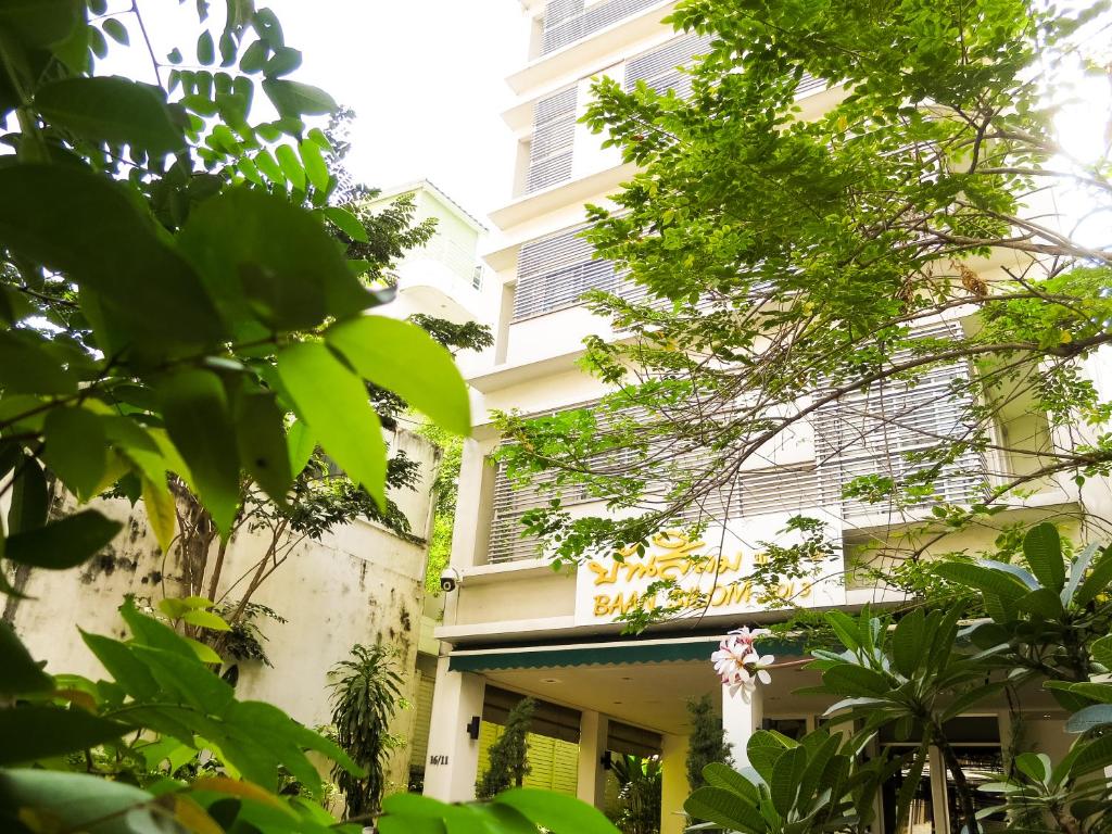 un edificio con árboles verdes delante de él en Baansilom Soi 3, en Bangkok