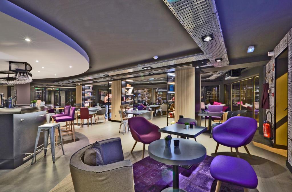 a restaurant with purple chairs and tables and a bar at Campanile Nancy Centre - Gare in Nancy