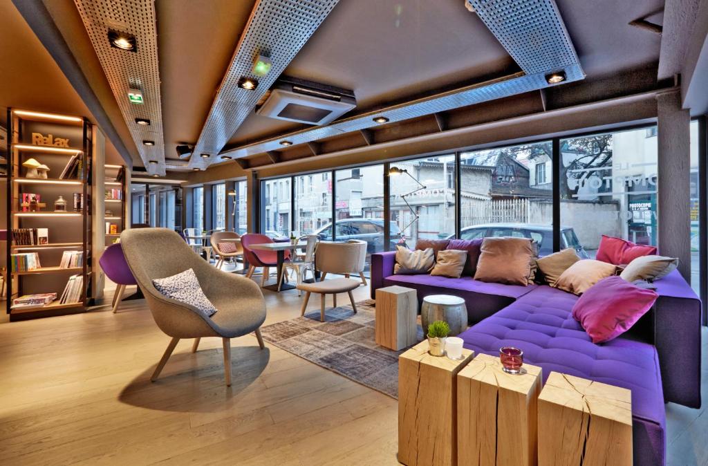 a living room with a purple couch and a table and chairs at Campanile Nancy Centre - Gare in Nancy