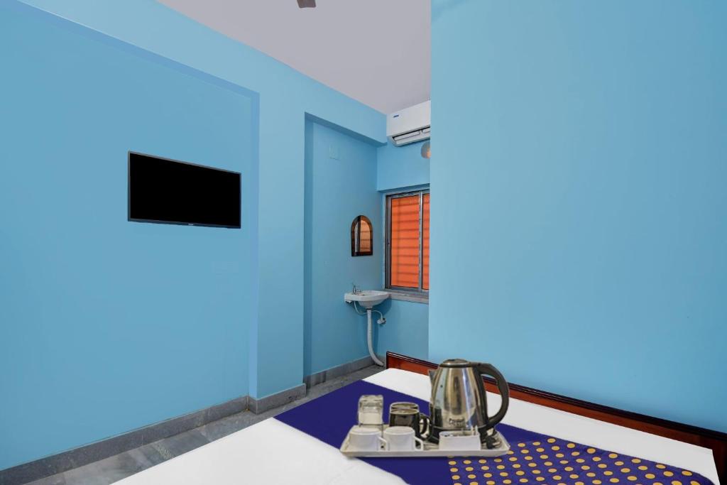 Habitación con paredes azules y mesa con hervidor de agua. en Hotel O Singh Guest House, en Calcuta