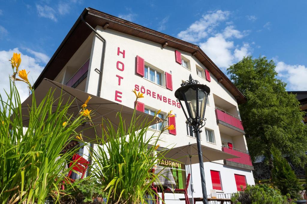 ein weißes Gebäude mit roten Fenstern und einem Straßenlicht in der Unterkunft Hotel Sörenberg in Sörenberg