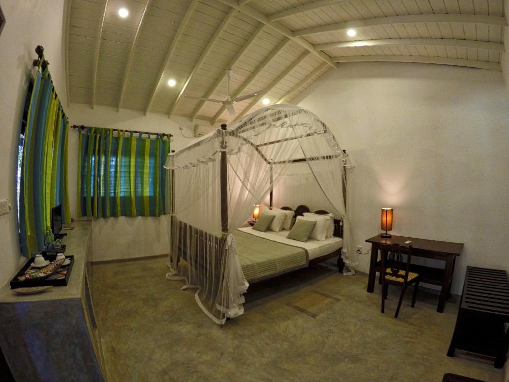 a bedroom with a canopy bed and a desk at The Horizon Hill Top Villa in Unawatuna