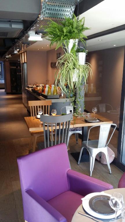 a dining room with a purple chair and a table with plants at Campanile Nancy Centre - Gare in Nancy