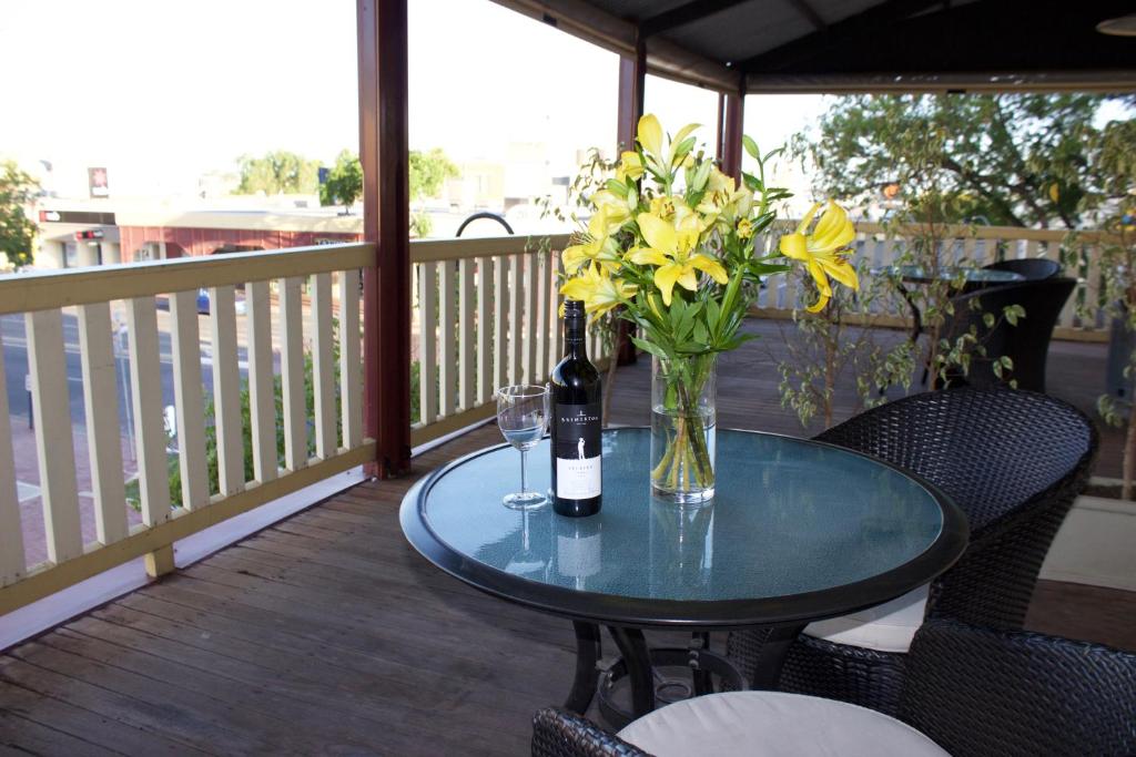 einen Tisch mit einer Vase Blumen und einer Flasche Wein in der Unterkunft Balcony On Sixth Lodge in Murray Bridge