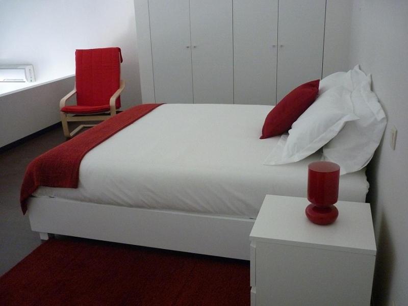 a bedroom with a white bed and a red chair at 12 Short Term in Porto