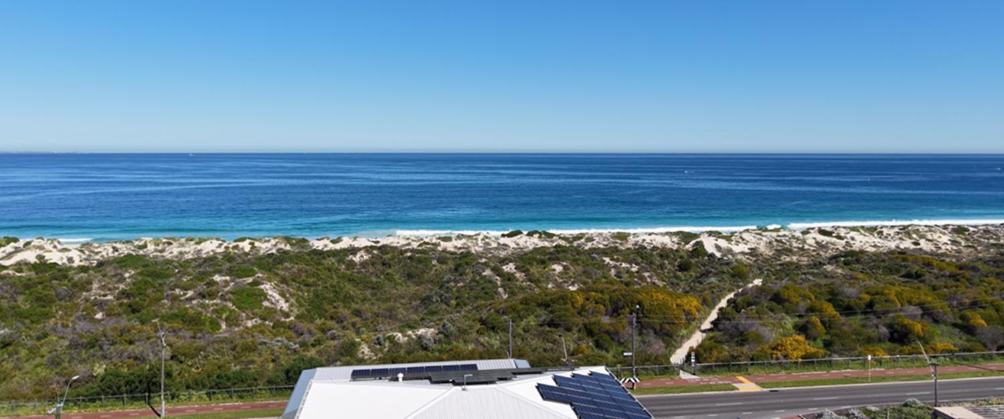 a bus parked on a road next to the ocean at Beach House Perth in Perth