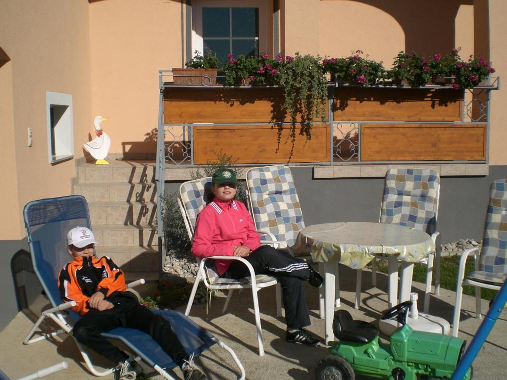 ルッツマンスブルクにあるApartment Karinのテーブル付きの庭の椅子に座っている子供2名