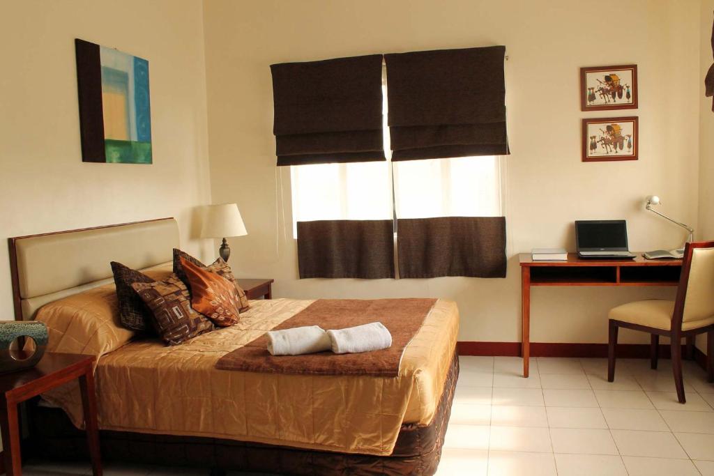 a bedroom with a bed with a desk and a window at La Casarita in Manila