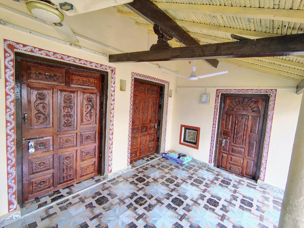 two wooden doors in a room with a tiled floor at Kutchi Niwas homestay dholavira in Dholovira
