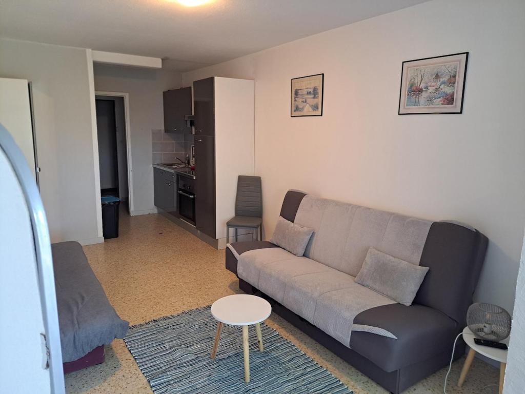 ein Wohnzimmer mit Sofa und Tisch in der Unterkunft Cap City, modeste rez-de-jardin 500m plage et du Port in Cap d'Agde