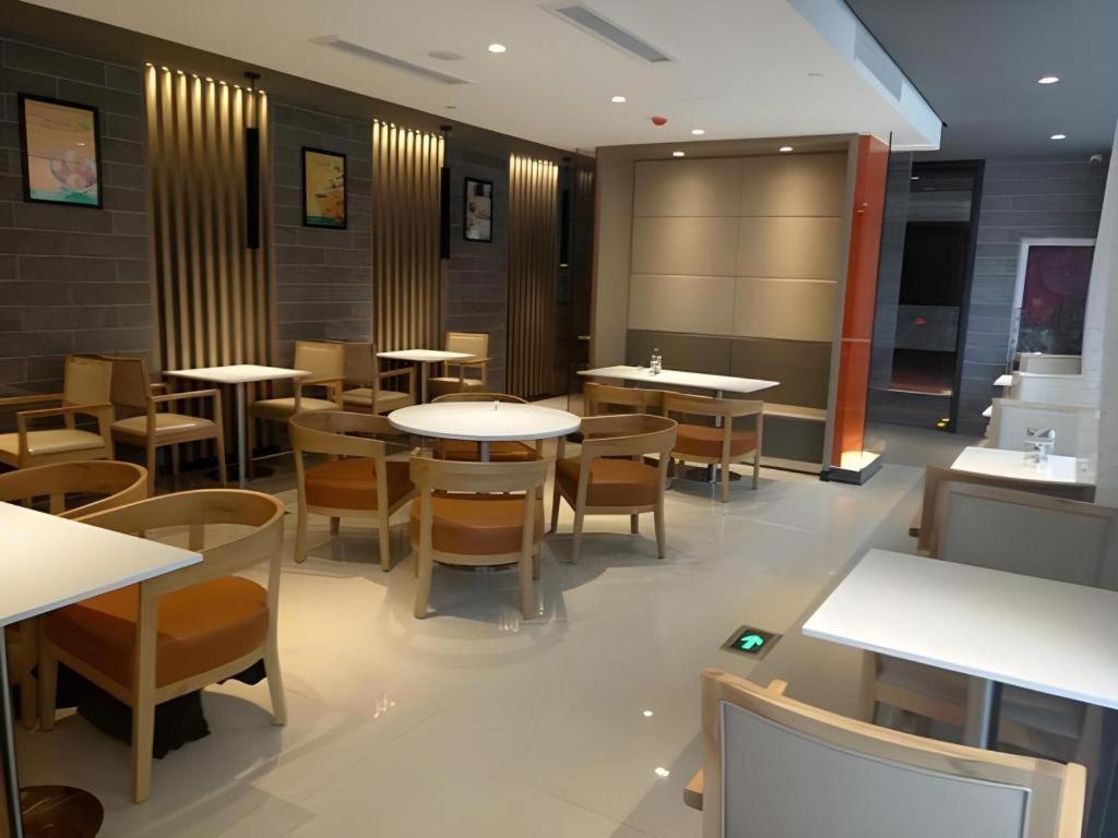 a restaurant with tables and chairs in a room at Jinjiang Inn Select Qingdao West Coast Coach Exhibition Center High-Speed Railway Station in Huangdao