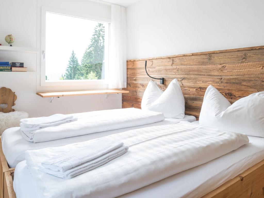 2 Betten mit weißer Bettwäsche und Kissen im Schlafzimmer in der Unterkunft Edelweiss Mira Neiv in Flims