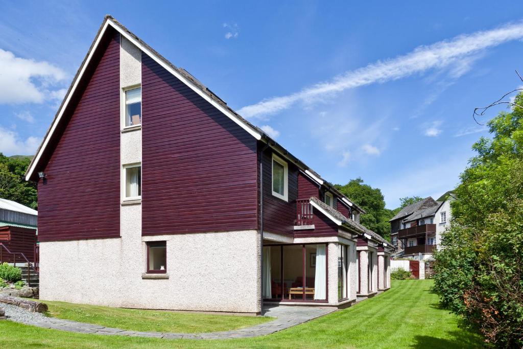 a red and white house with a yard at The Bridge Hotel Self Catering in Buttermere