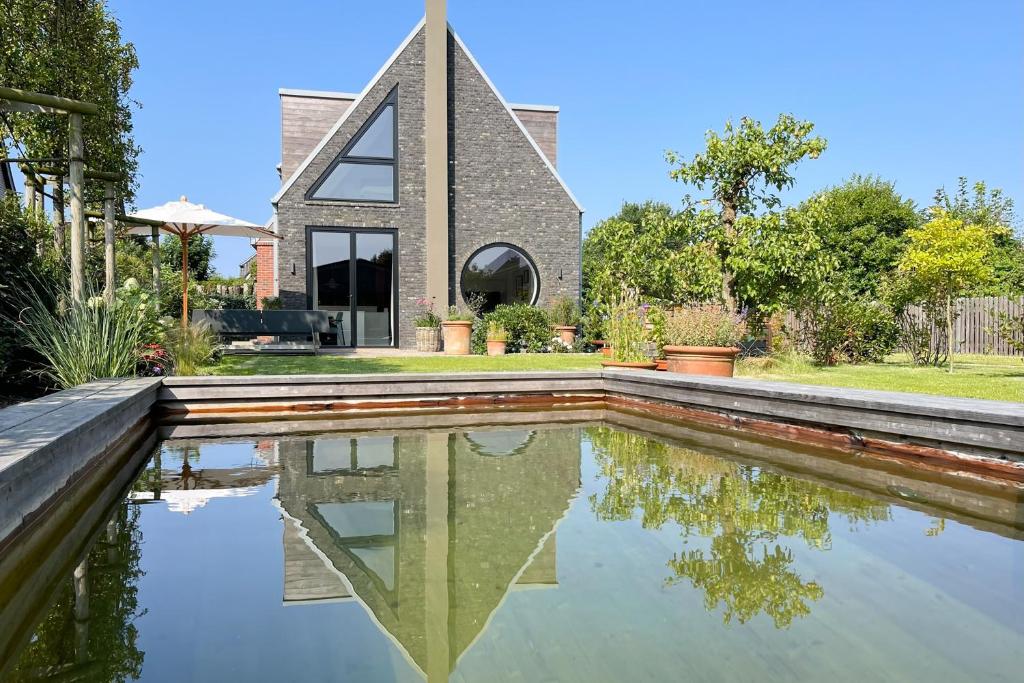 een huis met een reflecterend zwembad ervoor bij Sylter Strandholz in Westerland