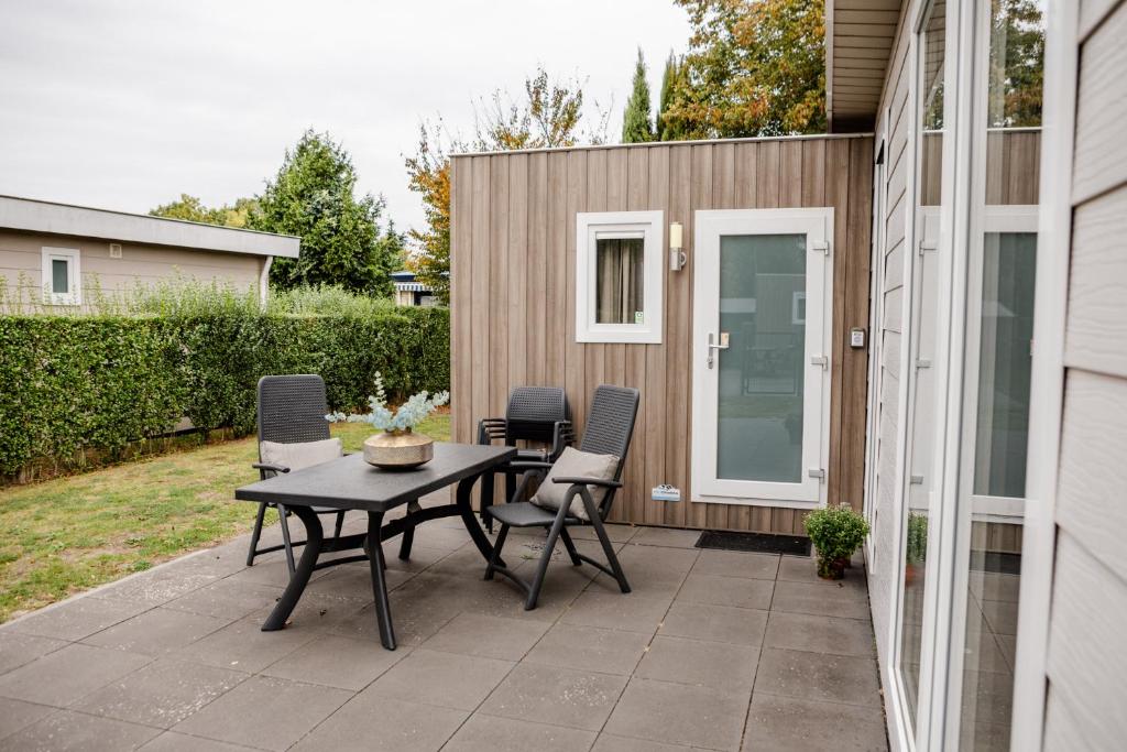 un patio avec une table et des chaises à côté d'un bâtiment dans l'établissement Modern chalet Heinkenszand VP104, à Heinkensand