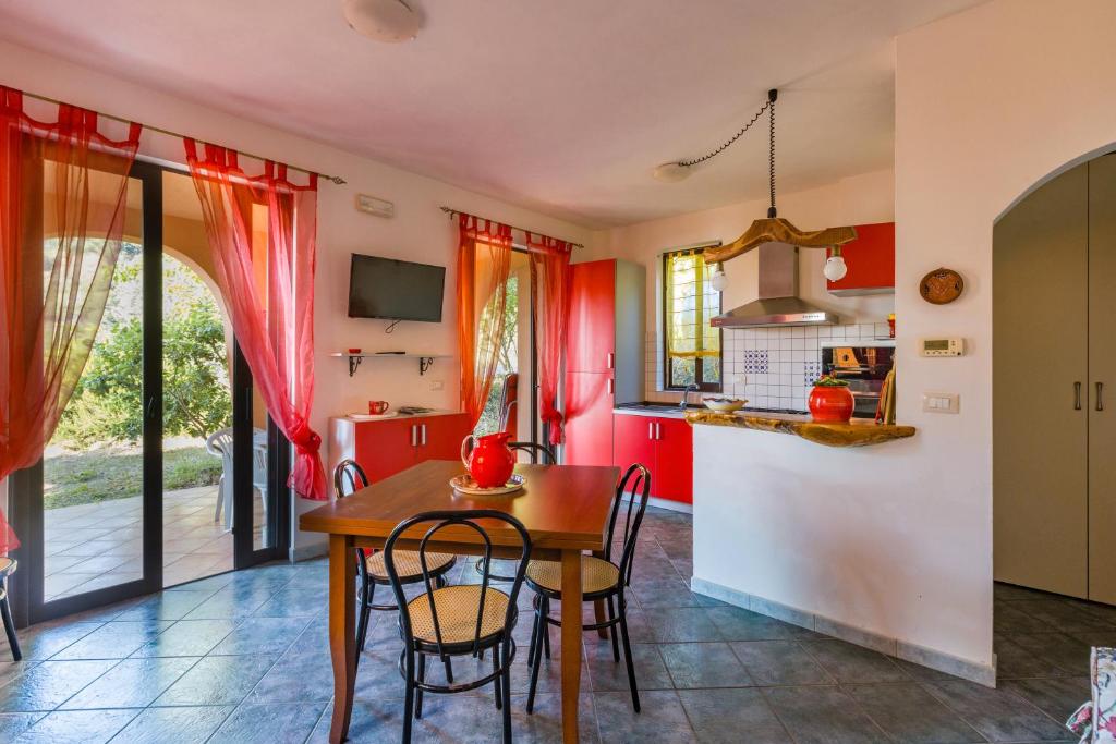 a kitchen with red walls and a table and chairs at Casa del Cedro Gioiosa Marea in Gioiosa Marea
