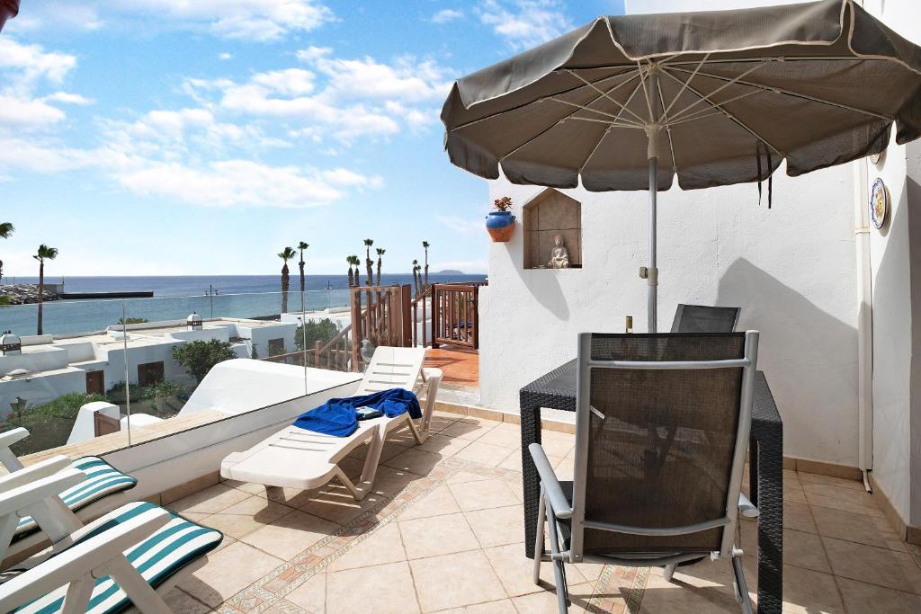 Un patio con una mesa y sillas y una sombrilla. en Puerto Chico 8, en Playa Blanca