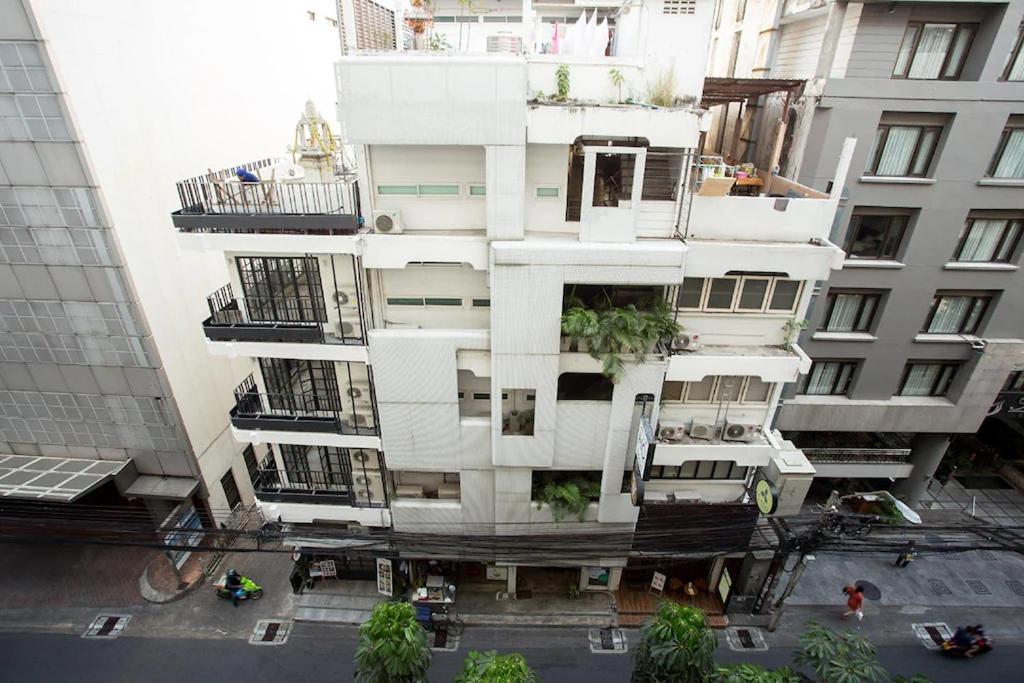 un edificio alto y blanco con plantas. en Qilombo Hostel Silom, en Bangkok