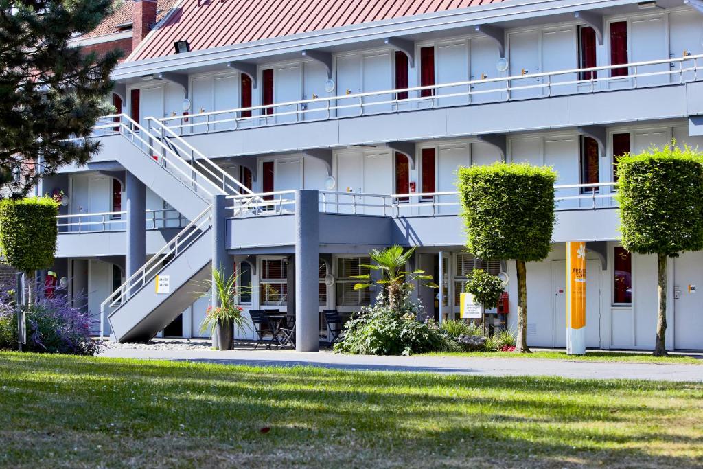 un grand bâtiment blanc avec des escaliers et des plantes dans l'établissement Premiere Classe Fleury Merogis, à Fleury-Mérogis