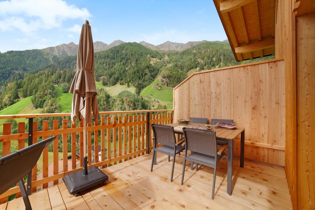 een terras met een tafel en stoelen en een parasol bij Herrischner Apartement 2 in Corvara in Passiria