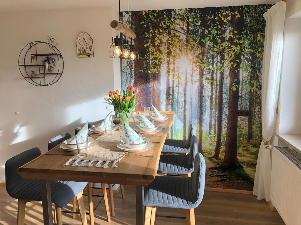 Una mesa de comedor con sillas y un cuadro de árboles. en Ferienwohnung Immenberg, en Dirlewang