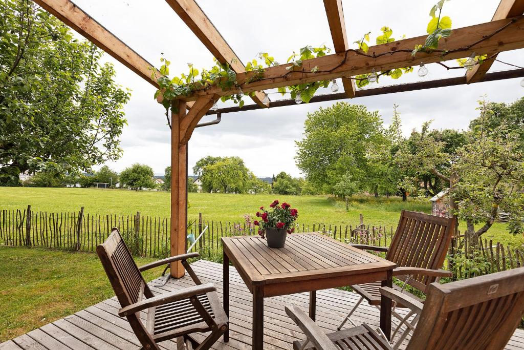 una mesa de madera y sillas en una terraza con pérgola en Auszeit, en Donaueschingen