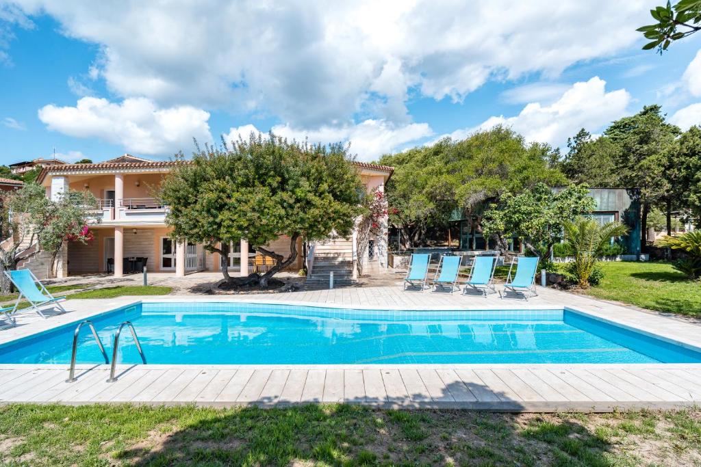 - une piscine en face d'une maison avec des chaises bleues dans l'établissement La Vela Arancione, à Orosei