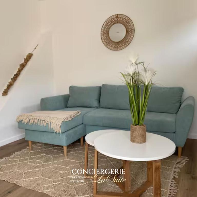 Una sala de estar con un sofá azul y una mesa. en L'impasse, en Cherbourg-en-Cotentin