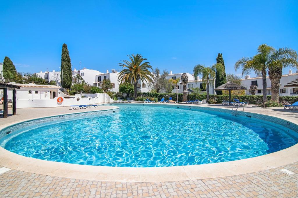 a swimming pool in a resort with palm trees and buildings at Apartamento São Rafael in Albufeira