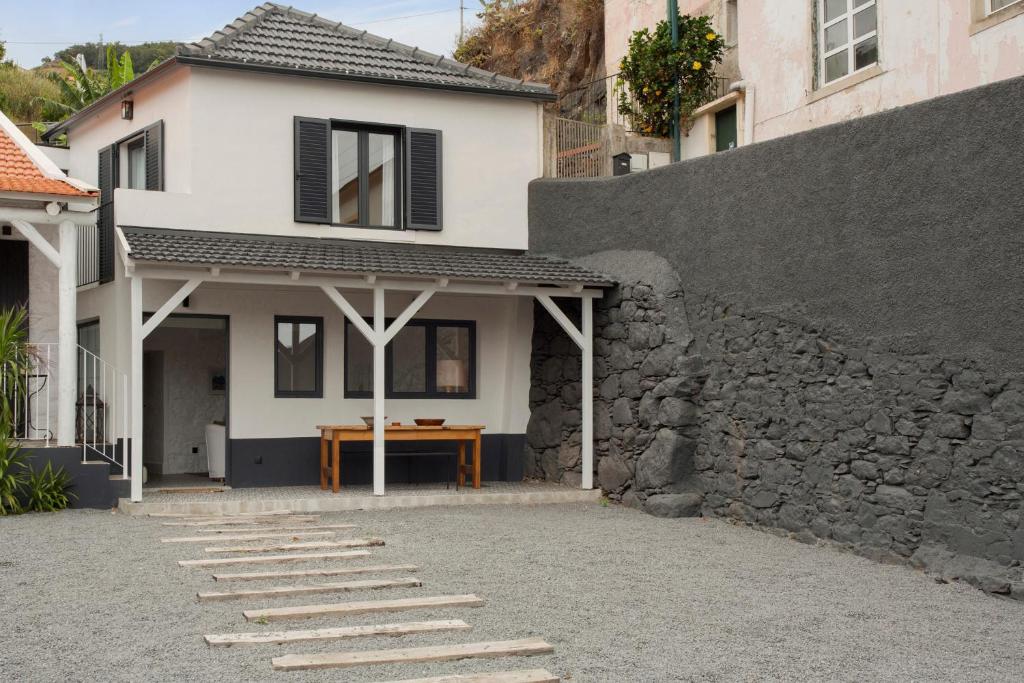 a white house with a stone wall and a table at The Village Loft in Caniço
