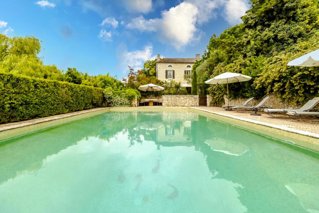 a swimming pool with blue water in front of a house at Chez Jacquou in Bouniagues